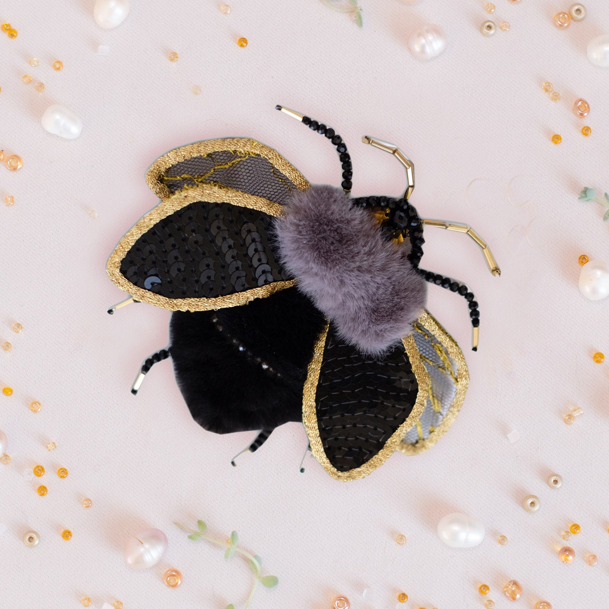 a black and gold bee with a purple fuzzy ball